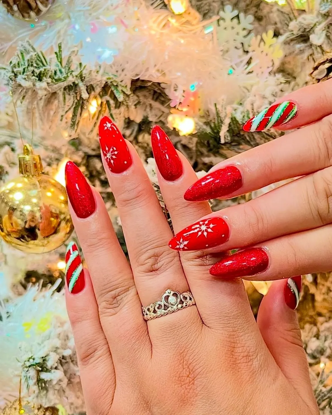 Glossy classic red almond nails with small festive accents.