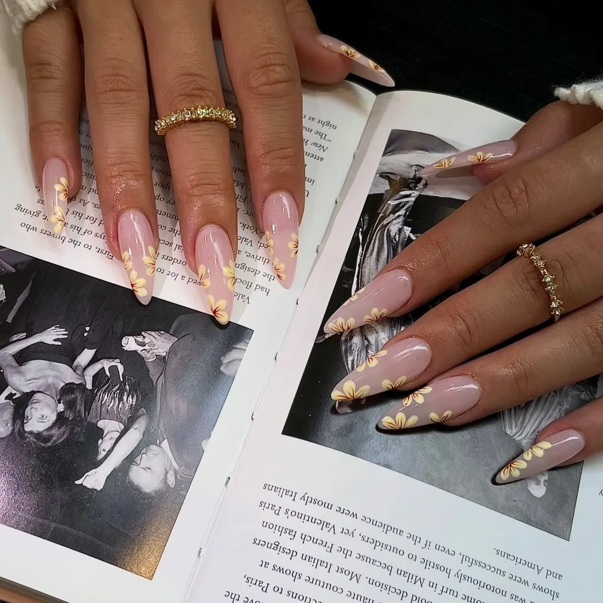 Long sheer-pink almond nails with raised gold dots along the tips.