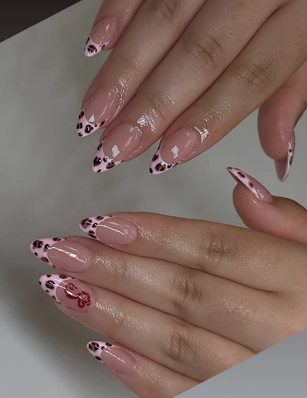 Sheer pink almond nails with leopard-print French tips.