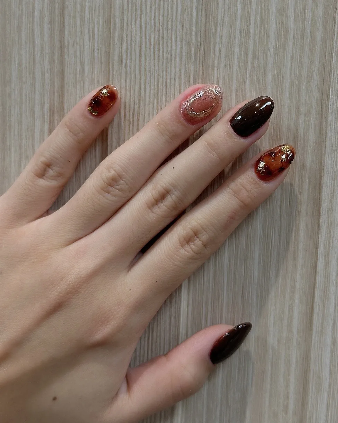 Short natural nails in glossy brown and amber tortoiseshell.